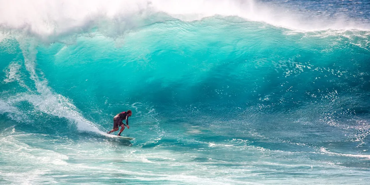 Surfer riding a powerful turquoise wave at Mount Maunganui beach in Tauranga New Zealand